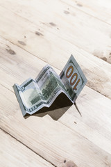 A conceptual shot of us dollar bill folded as to show an upward trend, growth in a business.