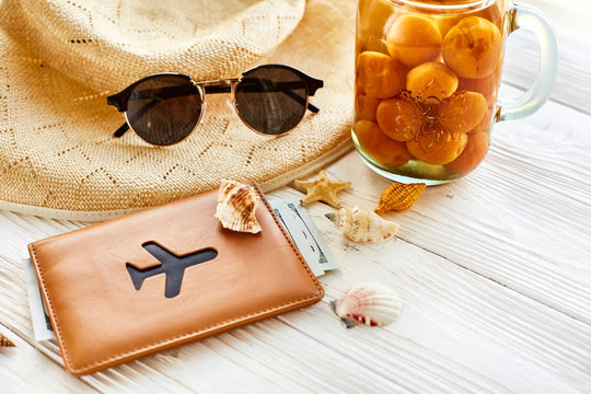 summer vacation concept. yellow cocktail juice with apricot, hat, sunglasses plane and shells and passport on white rustic wooden background. space for text. travel and summer holiday
