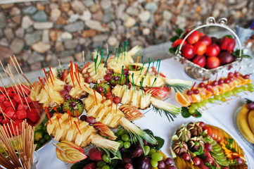 Table catering with different fruits such as watermelon, pineapple at wedding reception.