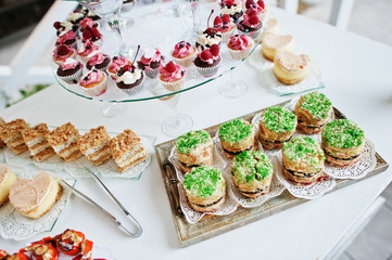 Table catering with different cakes and cupcakes at wedding reception.