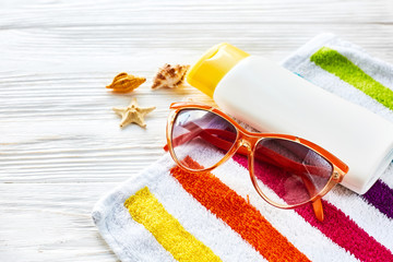 summer vacation concept. colorful towel, sunglasses, yellow sunscreen and star shells on white...