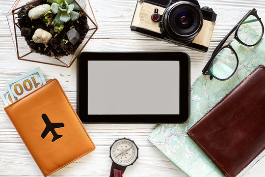 planning travel concept, space for text. tablet with empty screen, money map compass camera glasses wallet on white wooden background. time to travel wanderlust concept