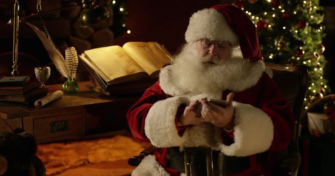 Santa Claus puts on his glasses, then fiddles with his smartphone
