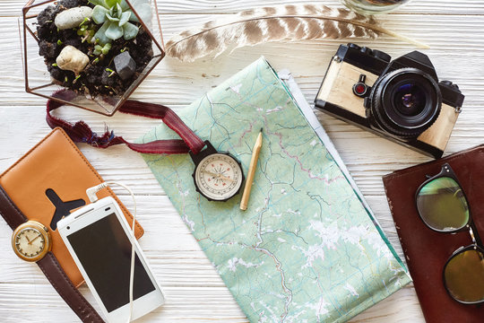 wanderlust and travel concept. compass and pencil on map exploring. passport money glasses photo camera on white wooden background. planning vacation. space for text. time to travel