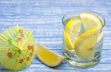 water with a lemon on a wooden background