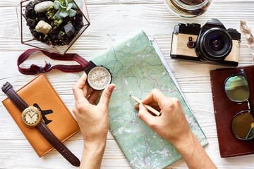 wanderlust and travel concept flat lay. hand holding compass and pencil on map exploring. passport...