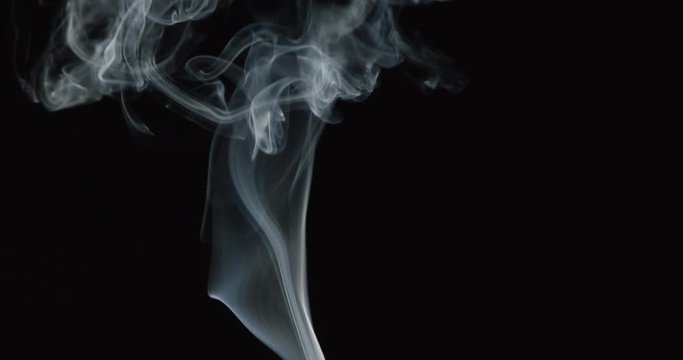 Smoke wisps and billows rise from bottom of frame and curl, slow motion
