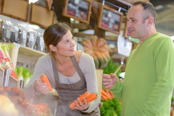 Sales assistant with customer, holding carrots