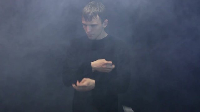 magician shows trick with card on black background.