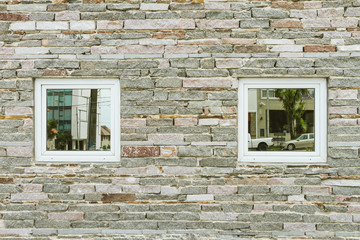 Two windows with mirrored glass on a stone wall