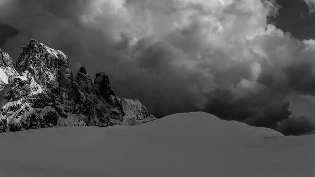 Sweeping, black-and-white timelapse across snowcapped Italian mountains.