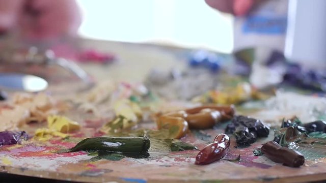Artist squeezes paint from tube onto the palette. Slow motion