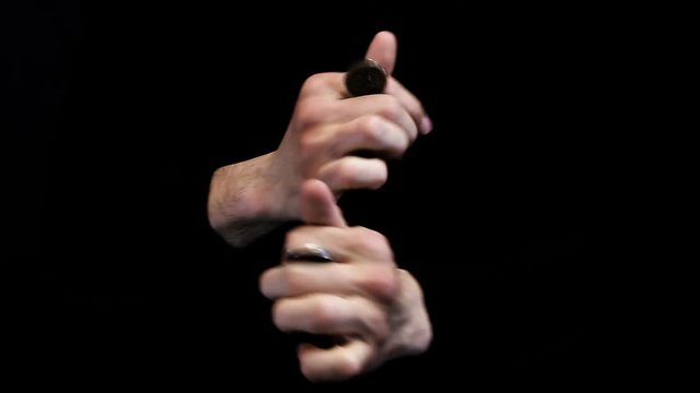 magician shows coin trick on black background