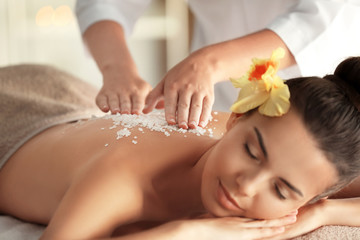 Fototapeta na wymiar Young woman getting massage with sea salt in spa salon