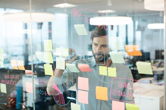 Young Businessman Writing On Glass While Planning