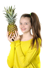 Happy young girl holding a large pineapple..