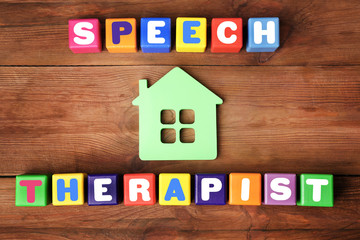 Colourful cubes with text SPEECH THERAPIST on wooden background