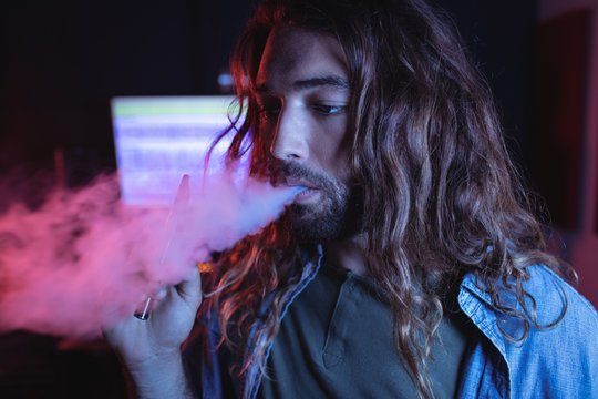 Male audio engineer smoking electronic cigarette