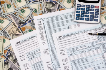 1040 tax from with us dollar banknote, pen and calculator.