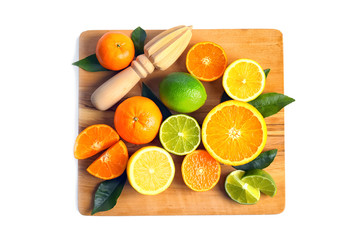 Wooden board with delicious citrus fruits and hand juicer on white background