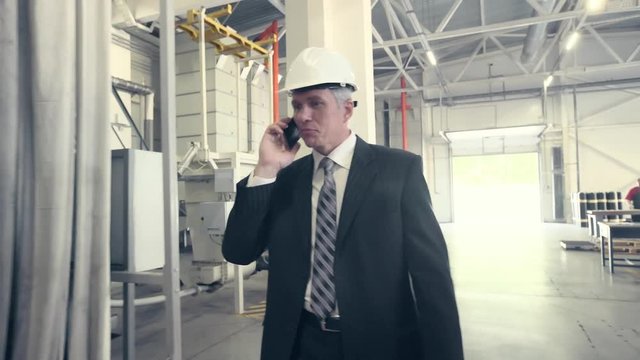 Man walking through factory and talking on phone
