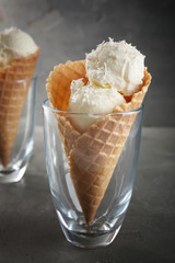 Glass with waffle cone and balls of coconut ice cream on grunge background