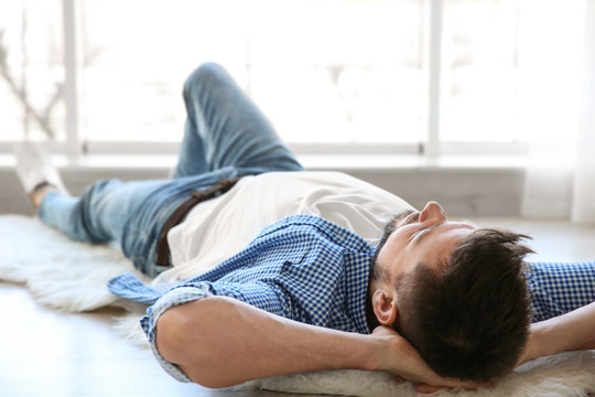 Happy young man lying on floor and taking rest