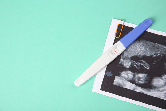 Ultrasound photo and pregnancy test on turquoise background