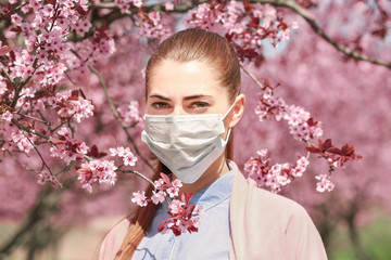 Young girl wearing face mask among blooming trees in park