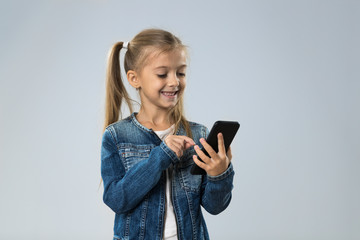 Fototapeta premium Little Teenage Girl Using Cell Smart Phone, Small Kid Happy Smiling Child Isolated Over Gray Background