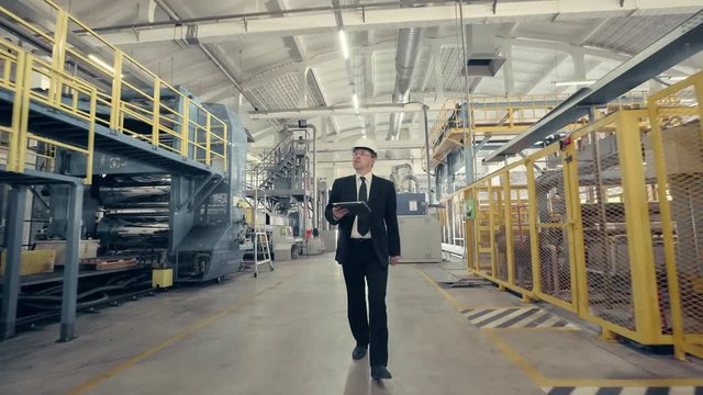 Businessman in hard hat walking through factory