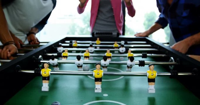 Happy graphic designers playing table football