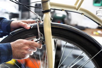 Regulacja hamulców rowerowych. Mężczyzna  wymienia klocki hamulcowe w rowerze