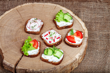 Assorted canapes with cucumber, radish and tomato and lettuce. Top view. The concept of healthy eating and vegetarianism.