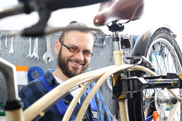 Mechanik w serwisie rowerowym. Mężczyzna, pracownik serwisu rowerowego montuje nowe siodło rowerowe. - obrazy, fototapety, plakaty