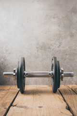  iron dumbbell on a wooden plank with gray background
