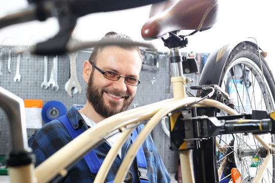 Mechanik w serwisie rowerowym. Mężczyzna, pracownik serwisu rowerowego montuje nowe siodło rowerowe.