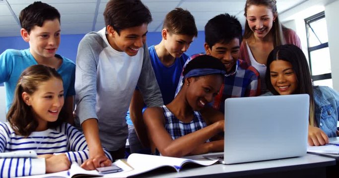 Group of mixed-race students using laptop in classroom