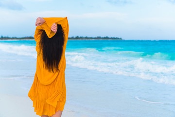 Young beautiful woman on tropical seashore in sunset. Back view of young girl in beautiful dress background the sea