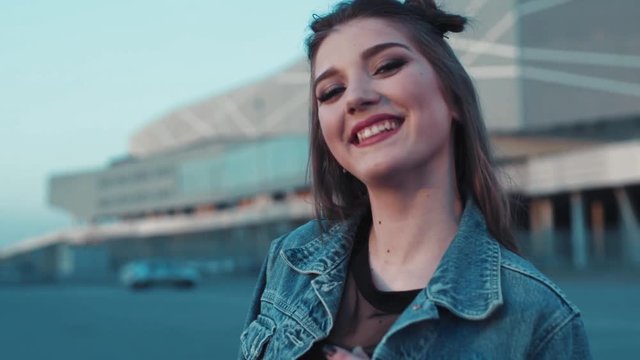 Portrait of young beautiful girl smiling towards the camera. Young stylish jeans wear. Cheerful mood, happiness. Active lifestyle. No people around.