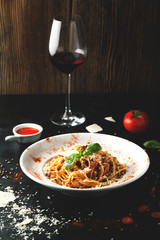 Delicious pasta of bolognese with meat, parmesan, basil and a glass of wine
