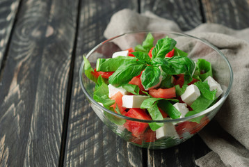 Detoxing diet salad: sorrel, tomatoes, feta cheese, basil on a wooden black table. Healthy food...