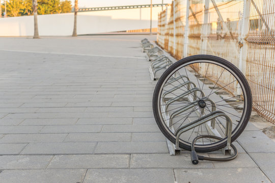 Fototapeta Stolen bicycle, Chained front bicycle wheel locked. A damaged bike wheel is all that is left, a single bicycle wheel on the street due to stealing.