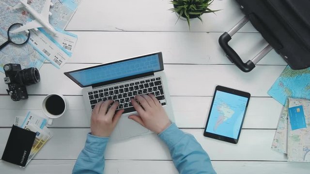 Top view traveler's hands using laptop computer digital tablet with map lying on white wooden desk