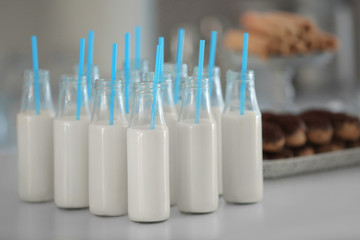 Bottles with milk and straws on table