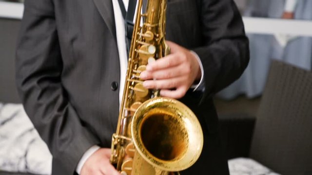 Saxophonist in a black suit playing on golden saxophone. Jazz music.