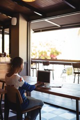Woman using laptop while having coffee