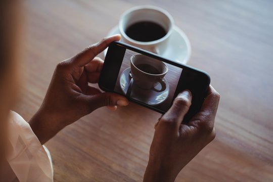 Hands of woman taking a clicking picture of black coffee