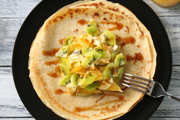 Plate with delicious pancakes and fruits on table