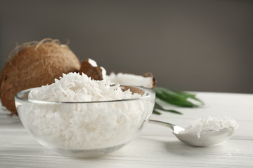 Glass bowl with coconut flakes on wooden table